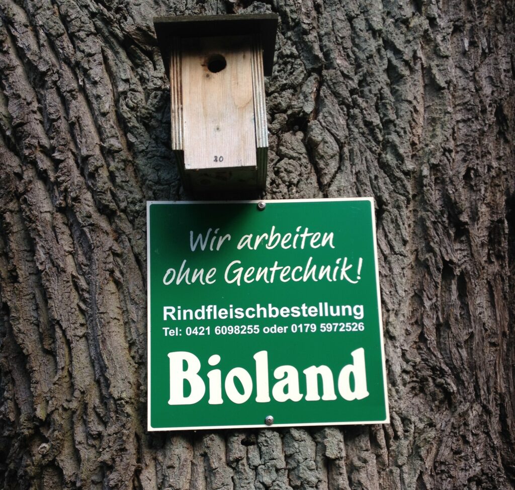 Infoschild: "Wir arbeiten ohne Gentechnik! Rindfleischbestellung Tel: 0421 6098255 oder 0179 5972526, Bioland"